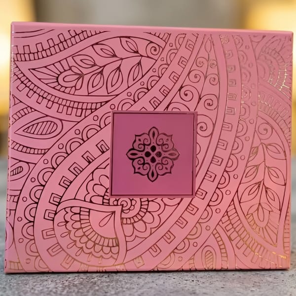 Pink box with intricate gold patterns and a dark pink square with a gold emblem.