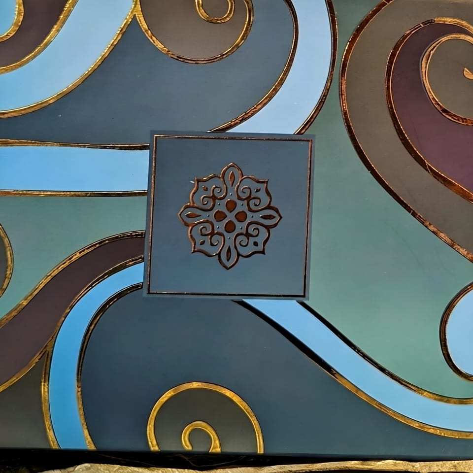 A decorative box with blue, teal, and purple waves outlined in gold, featuring a gold medallion.